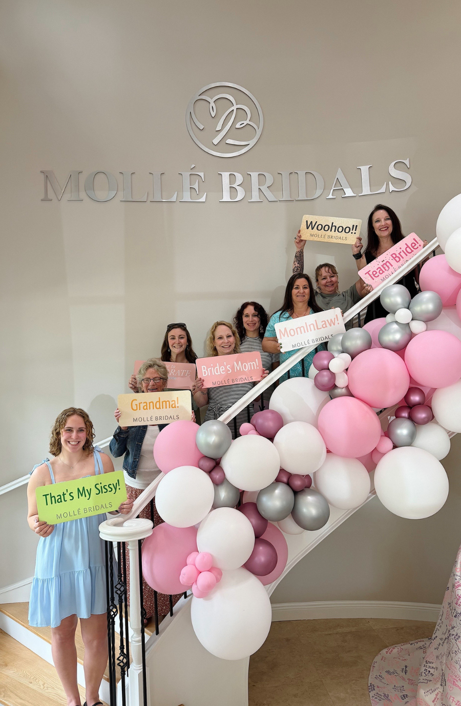 A group of women standing on a staircase, holding colorful signs that say 