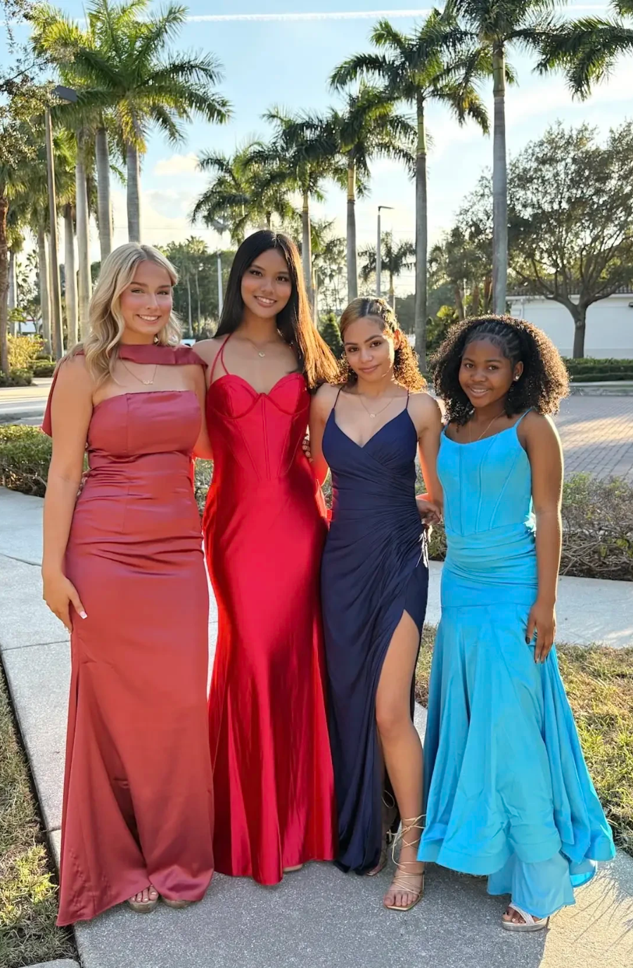 four models are wearing a variety of colorful prom dresses