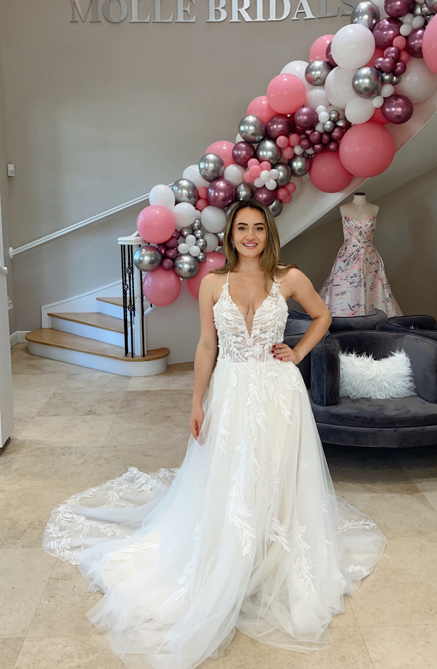Model is wearing an a-line bridal dress with spaghetti straps and a tulle skirt
