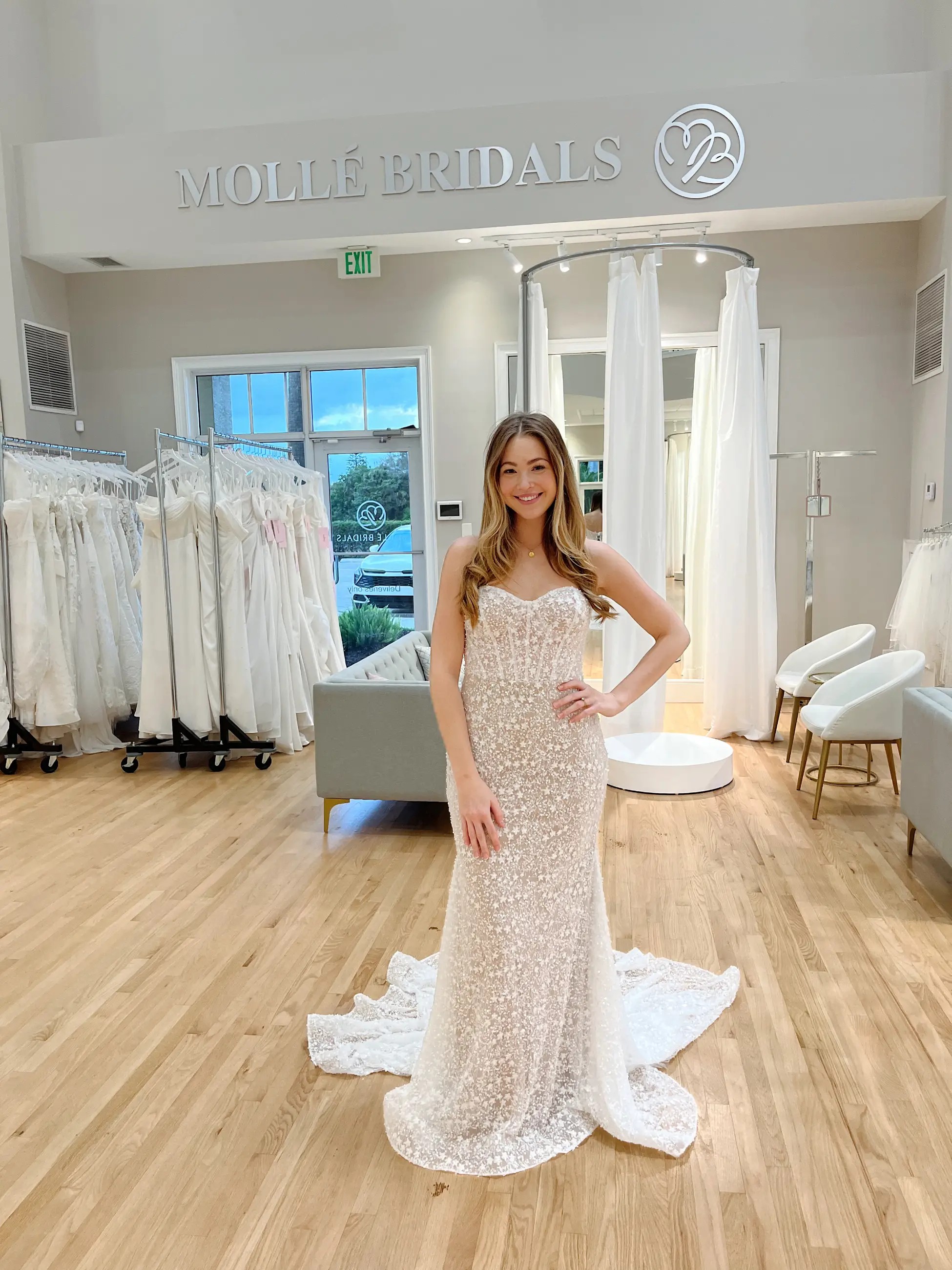 Model is wearing a strapless column bridal gown with intricate beadwork and a blush undertone 