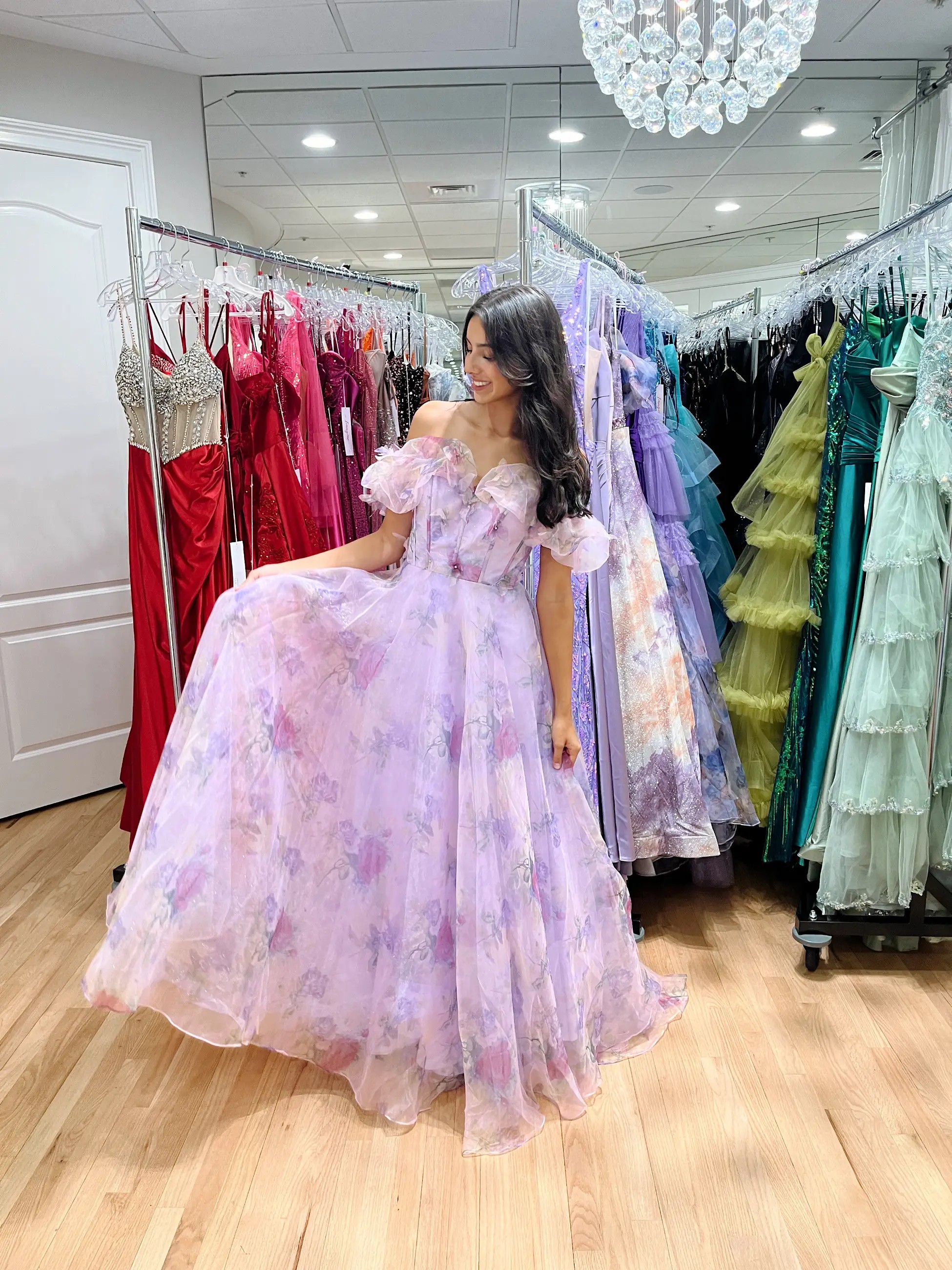 Model is wearing a floral purple a-line evening dress with off the shoulder puffy sleeves