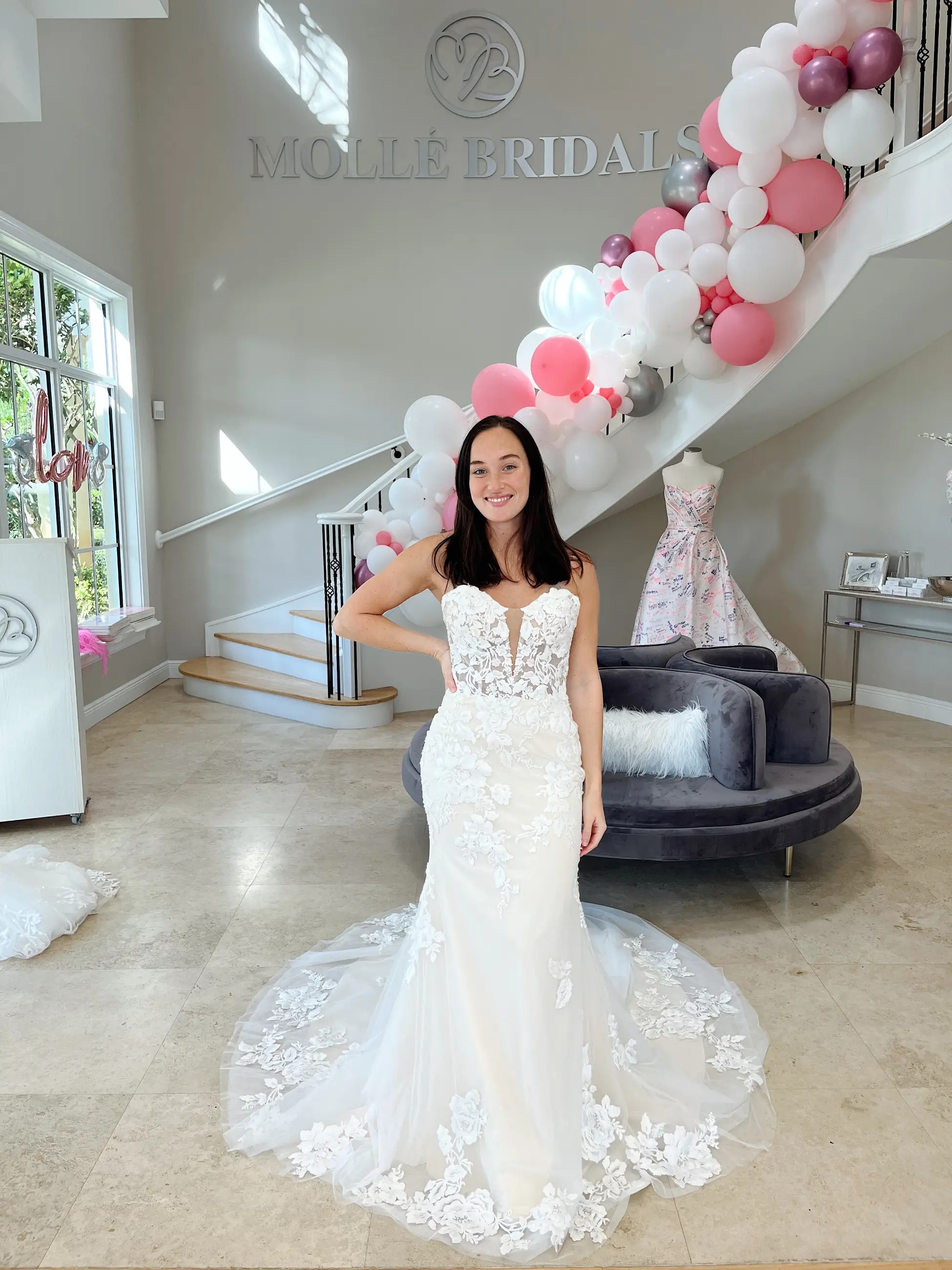 Model is wearing a strapless fit and flare wedding dress with floral lace and a plunging neckline 