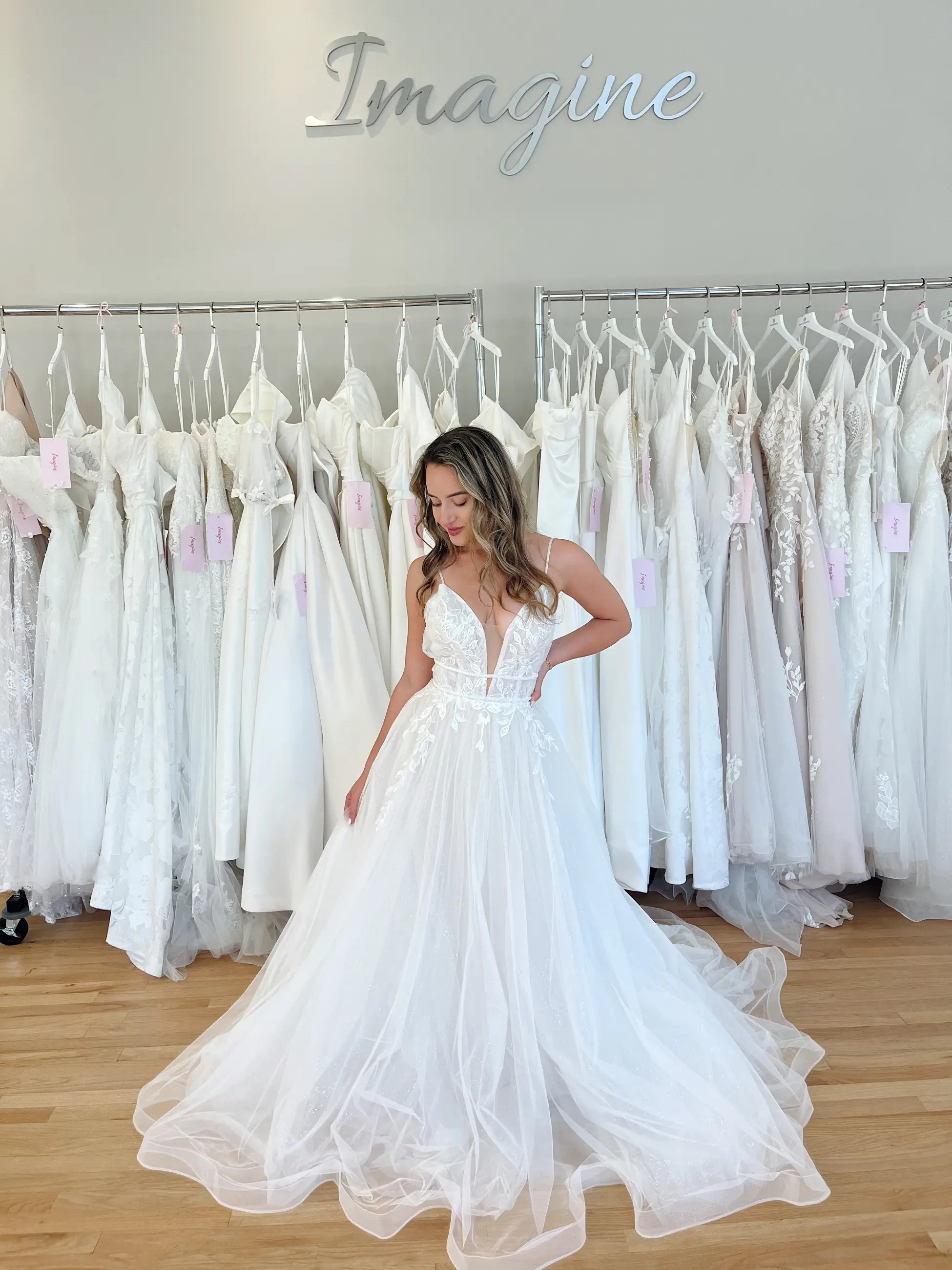 Model is wearing an a-line wedding gown with spaghetti straps and a full tulle skirt with a plunging neckline