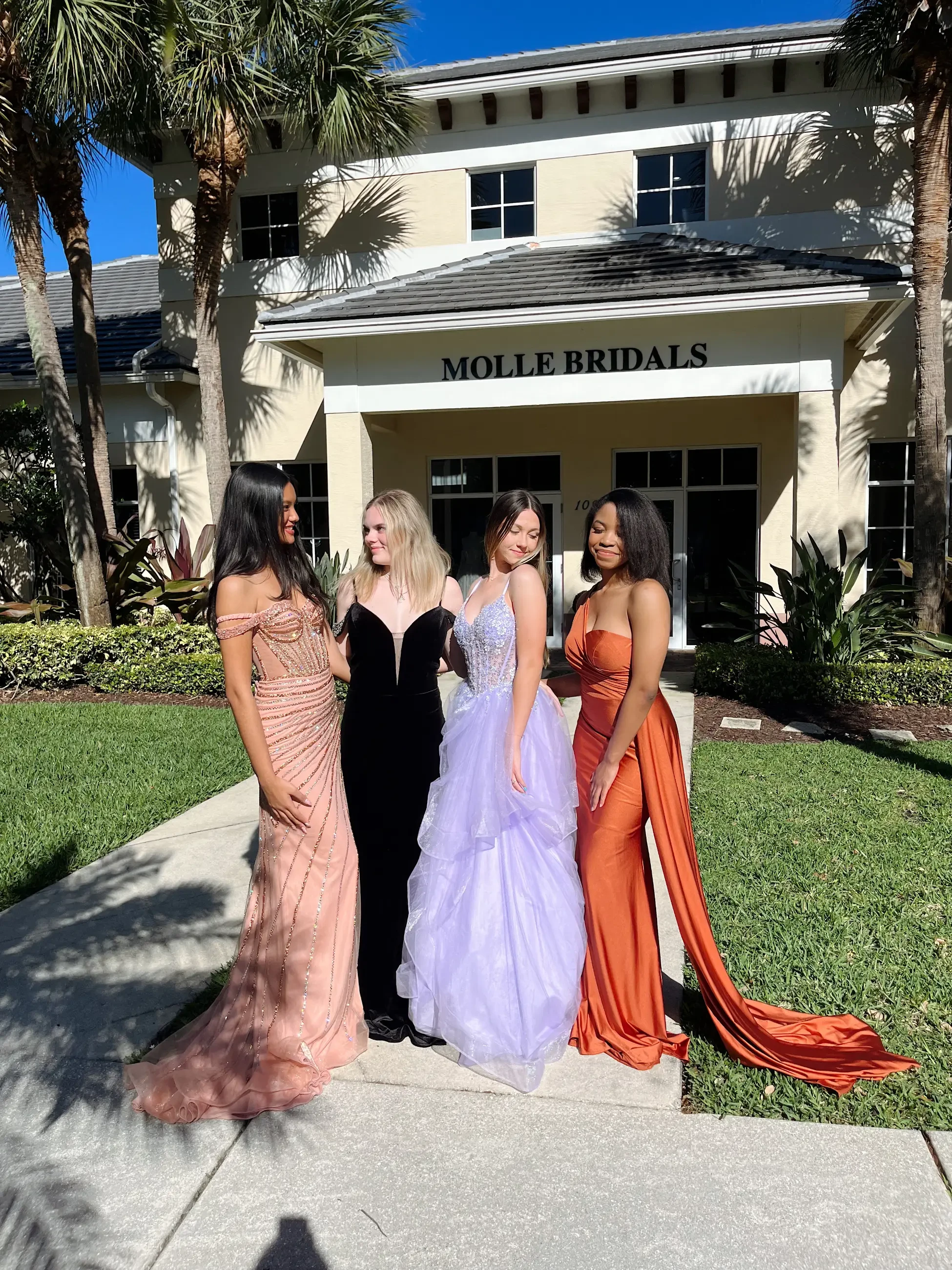 image shows four models wearing floor length evening gowns from molle bridals