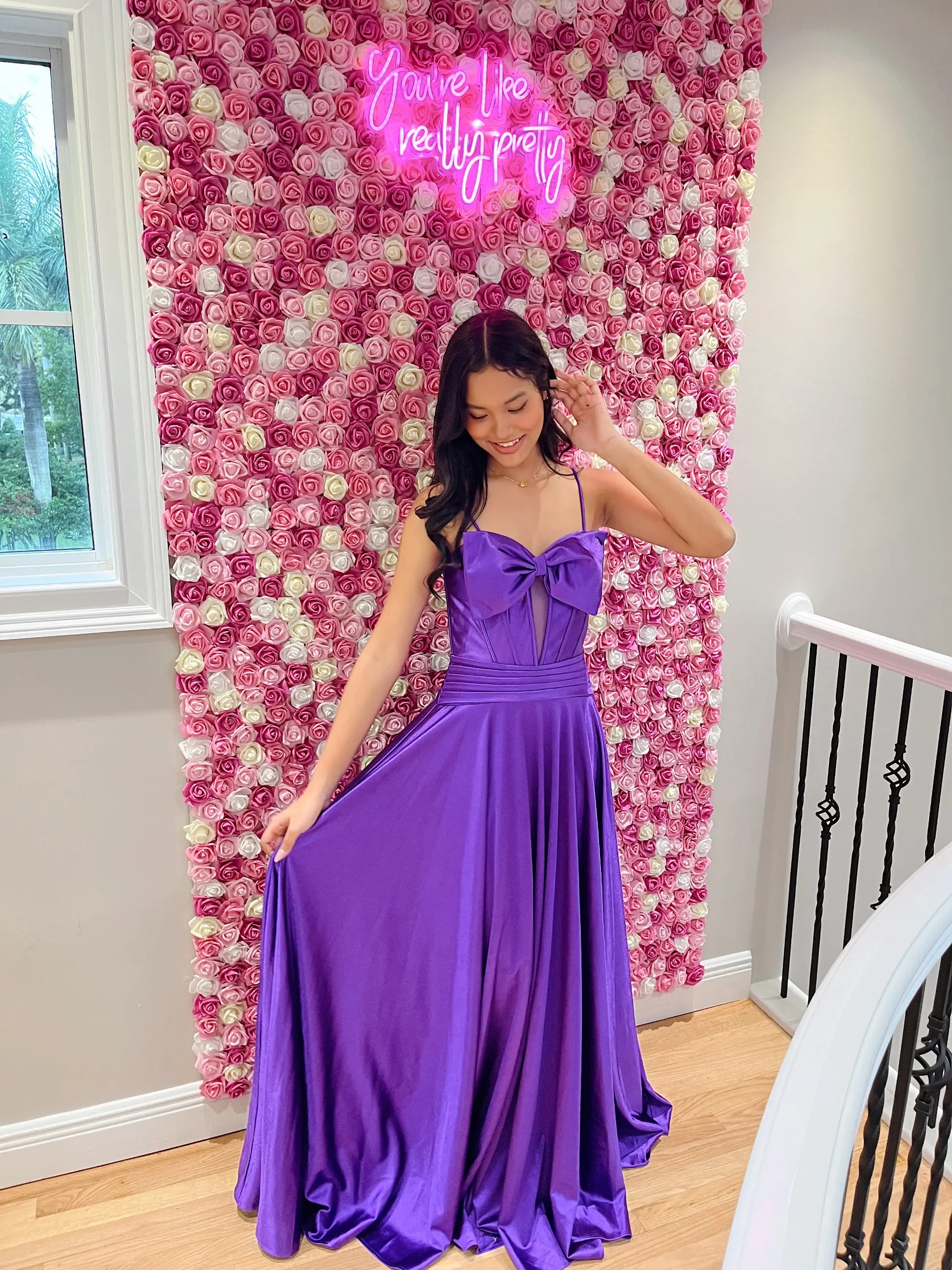Model is wearing a purple sleeveless a-line gown with spaghetti straps