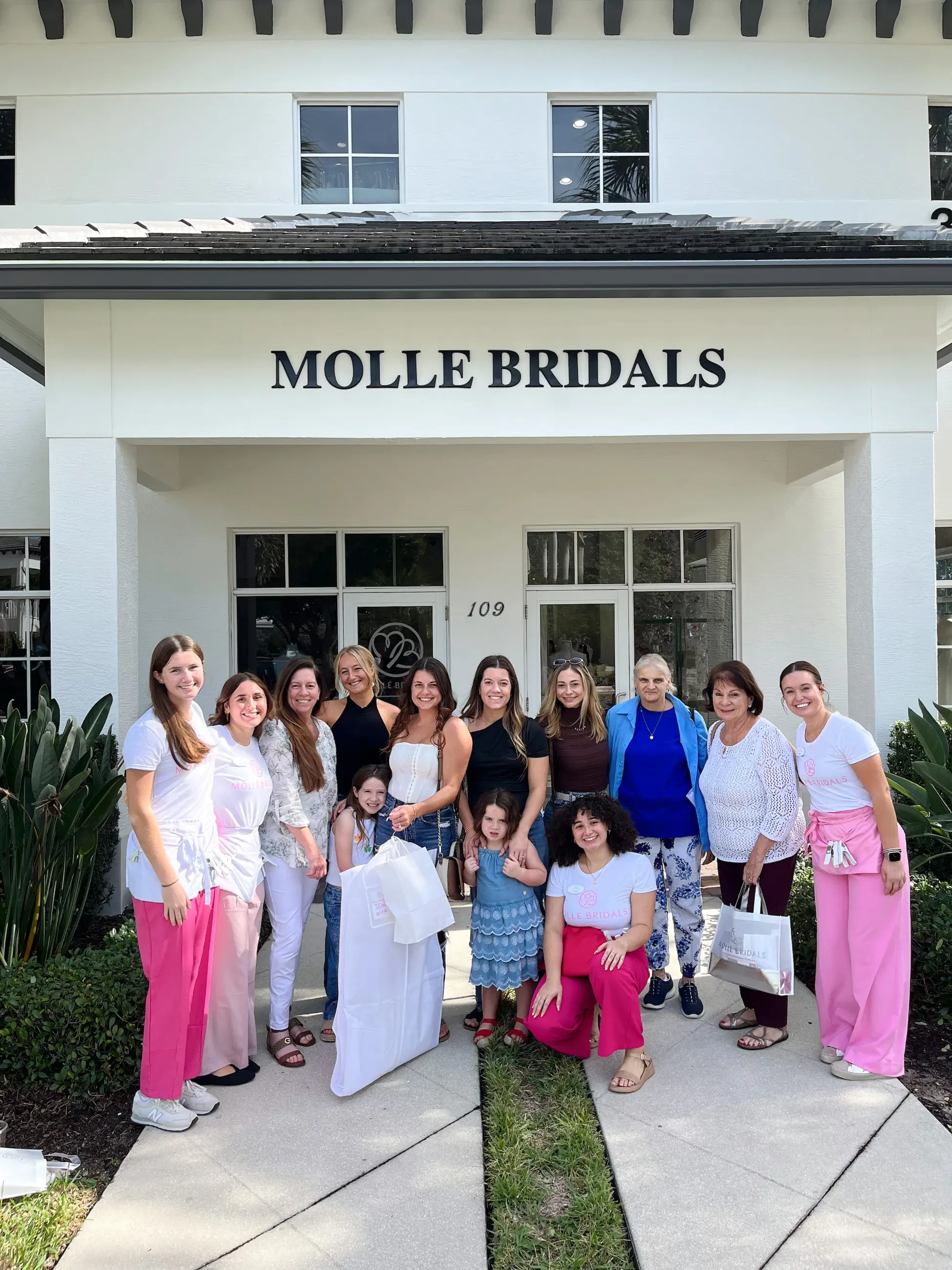 A group of women and two girls stand smiling outside 