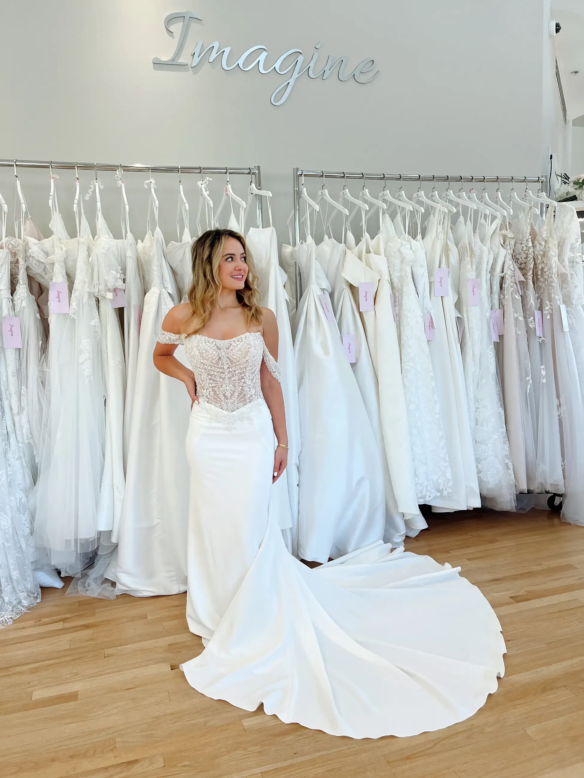 model is wearing an off the shoulder fit and flare basque waist bridal gown
